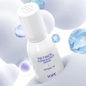 Biała butelka IOPE Retinol Super Bounce Serum na tle miękkich, kulistych kształtów w odcieniach bieli i błękitu. Wokół unoszą się przezroczyste, perłowe i niebieskie bąbelki, sugerujące zaawansowaną formułę serum oraz jego nawilżające i ujędrniające właściwości. Elegancki design opakowania oraz delikatne, futurystyczne tło podkreślają innowacyjność i skuteczność produktu.