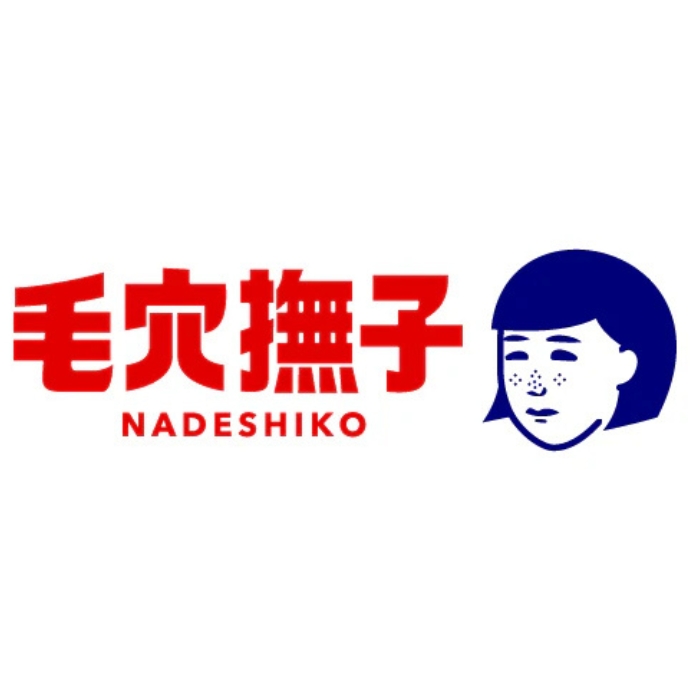 Logo marki Keana Nadeshiko – stylizowana ilustracja twarzy kobiety z grzywką i drobnymi kropkami na policzkach, symbolizującymi rozszerzone pory. Twarz wykonana jest w granatowym kolorze, co kontrastuje z czerwonymi japońskimi znakami obok. Poniżej znajduje się angielska nazwa „NADESHIKO” zapisana dużymi, czerwonymi literami. Logo ma minimalistyczny i nowoczesny charakter, nawiązujący do japońskiej pielęgnacji skóry.