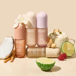 "Zestaw czterech perfum do włosów marki Kitsch w różnych wariantach zapachowych: Amber Shores, Warm Sugar, Sheer Violet i Pistachio Latte. Flakoniki ustawione pionowo i poziomo na jasnobeżowym tle, otoczone wizualnymi odniesieniami do nut zapachowych – kokosem, cynamonem, wanilią, pistacjami, malinami, limonką oraz filiżanką z bitą śmietaną i orzechami."