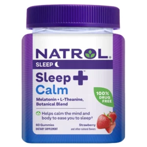 Zbliżenie na słoik Natrol Sleep+ Calm. Na białej etykiecie fioletowe i niebieskie napisy informują o składnikach suplementu: melatoninie, L-teaninie i mieszance botanicznej. Na dole etykiety widoczna jest grafika truskawek, sugerująca owocowy smak produktu. Produkt zawiera 60 żelków i jest oznaczony jako dietary supplement (suplement diety).