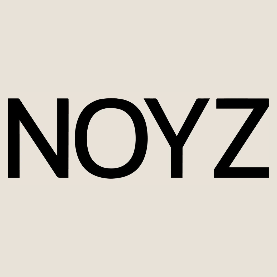 „Logo marki NOYZ – czarny napis ‘NOYZ’ na jasnobeżowym tle, prosty i nowoczesny krój pisma.”