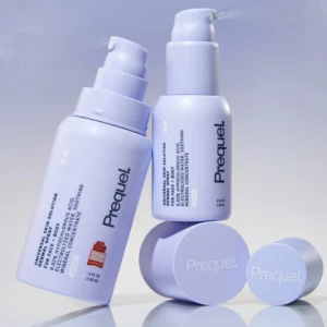 Prequel Universal Skin Solution Spray - dwa lawendowe opakowania kojącej mgiełki do twarzy i ciała z kwasem podchlorawym 0,02%, pokazane z pompkami rozpylającymi delikatną mgłę. Minimalistyczna fotografia produktowa na chłodnym, jasnofioletowym tle.