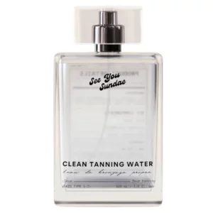 Zdjęcie przedstawia szklaną, bezbarwną butelkę z napisem Clean Tanning Water - produkt sugerujący kosmetyk samoopalający o lekkiej konsystencji i stopniowalnym przyciemnieniu twarzy.