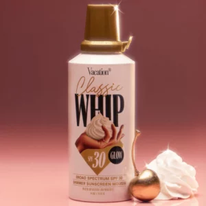 produkt Classic Whip w wersji Glow na stłumionym, ciemnym tle. Obok produktu leży bita śmietana mająca sugerować konsystencję produktu oraz złota wiśnia