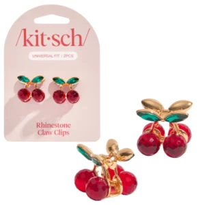 Zestaw dwóch klipsów do włosów w kształcie wiśni marki Kitsch, zaprezentowany na różowej karcie produktu z napisem „Rhinestone Claw Clips”. Obok widoczne są oba klipsy z bliska – czerwone kuleczki, zielone liście i złote wykończenie.