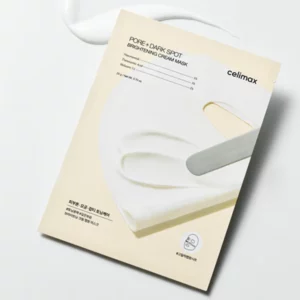 Opakowanie maski rozjaśniającej Pore Dark Spot Brightening Cream Mask marki Celimax, na tle rozmazanej plamy białego kremu.