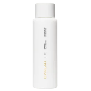 Minimalistyczna, biała butelka Cyklar Ceramide Milky Essence z czarnymi napisami i złotym logo, o pojemności 236 ml.