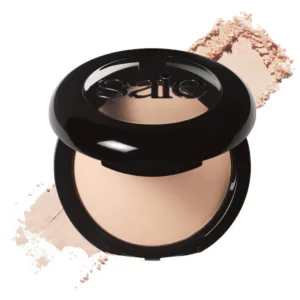 Otwarty puder Saie Slip Tint w odcieniu Translucent 2 – Light to Medium, z rozsypanym produktem w tle.