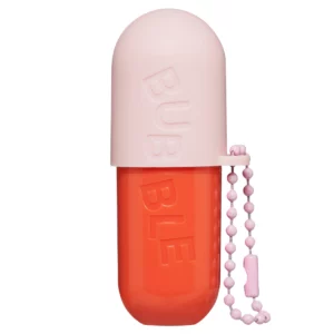 Zbliżenie na balsam do ust Bubble Tell All Lip Balm w designerskim opakowaniu przypominającym kapsułkę, w kolorach różowym i pomarańczowym, z różowym breloczkiem.