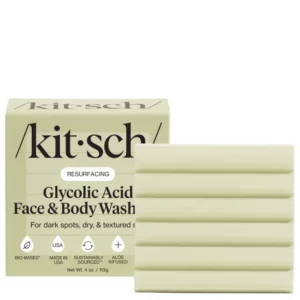 Kostka do mycia twarzy i ciała Kitsch Glycolic Acid Face & Body Wash w jasnozielonym opakowaniu z dużym czarnym logo marki i widoczną żłobioną kostką mydła obok.