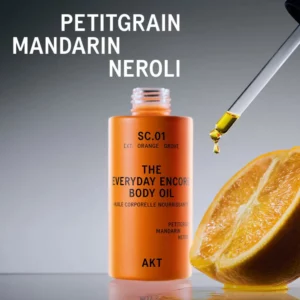 Pomarańczowa butelka olejku do ciała AKT z pipetą i kroplą olejku nad połówką soczystej pomarańczy, z napisem „Petitgrain, Mandarin, Neroli”.