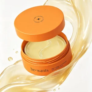 Otwarty pomarańczowy słoiczek be+wants Deep Toning Glutathione Eye Serum Patch z hydrożelowymi płatkami pod oczy, otoczony złocistą, połyskującą esencją.