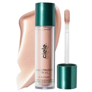 Ciele Glow & Protect Highlighter SPF 50 w odcieniu jasnoróżowym, w przezroczystym opakowaniu z zieloną nakrętką i aplikatorem, na tle rozprowadzonego produktu.