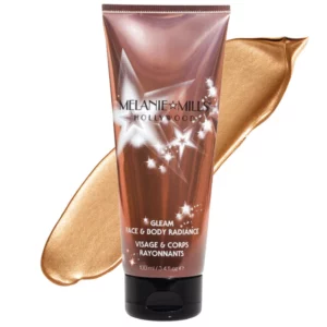 Tubka 100 ml Melanie Mills Gleam Face & Body Radiance Peach Deluxe na tle smugi produktu w odcieniu brzoskwiniowo-złotym.