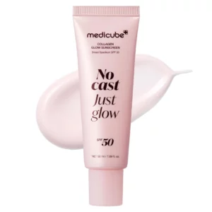 Zbliżenie na tubkę kremu przeciwsłonecznego Medicube No Cast Just Glow SPF 50+ w pastelowo-różowej tonacji, z rozprowadzoną kroplą kremu obok. Minimalistyczna, elegancka prezentacja produktu.