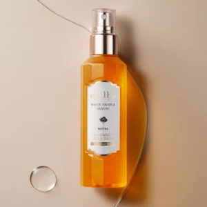 Butelka d’Alba White Truffle Royal Intensive Serum w odcieniu bursztynowym, leżąca na jasnym tle z delikatnym połyskiem — eleganckie opakowanie z złotą pompką i białą etykietą podkreśla luksusowy charakter produktu.
