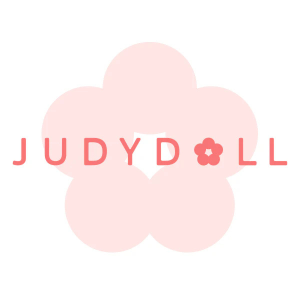 Logo marki Judydoll w odcieniach różu – stylizowany napis „JUDYDOLL” z małym kwiatkiem zastępującym literę „O”, umieszczony na tle dużego, jasnoróżowego kwiatu o pięciu płatkach.