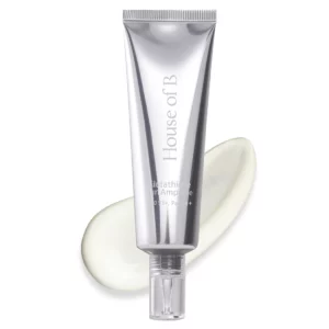 Zbliżenie na srebrną tubę House of B Glutathione Sun Ampoule SPF 50 na tle białym, z delikatnie rozlaną kremową teksturą produktu – elegancka prezentacja formuły.