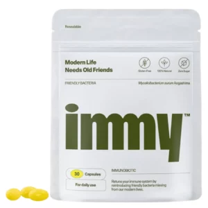 Biała saszetka suplementu immy z dużym oliwkowym logo i oznaczeniem „30 capsules”, leżąca na białym tle obok trzech żółtych kapsułek.
