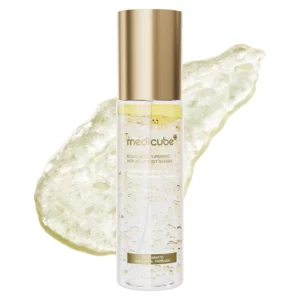Butelka Medicube Turmeric Vitamin Gold Jelly Mist Serum na tle złotej, żelowej tekstury produktu.