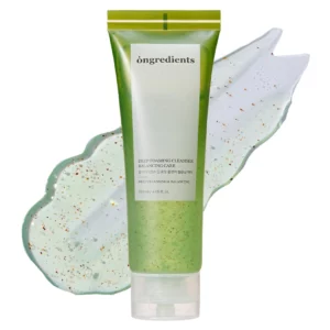 „Zielony żel oczyszczający Ongredients Deep Foaming Cleanser w tubie 120 ml, przedstawiony na tle rozsmarowanej tekstury produktu z widocznymi drobinkami peelingującym.