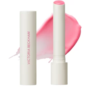 Victoria Beckham Posh Balm – koloryzujący balsam do ust w jasnoróżowym odcieniu, minimalistyczne opakowanie i półtransparentna smuga koloru.