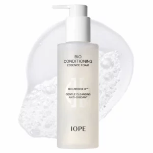 Butelka pianki do mycia twarzy IOPE Bio Conditioning Essence Foam z pompką, ustawiona na białym tle z widoczną strukturą piany w tle. Na opakowaniu widoczna nazwa produktu i informacja o działaniu antyoksydacyjnym.