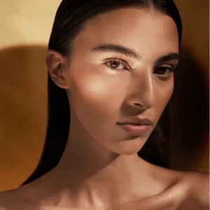 Portret modelki o ciepłej karnacji z matowym bronzerem, subtelnie podkreślone kości policzkowe i naturalny efekt opalenizny bez połysku.