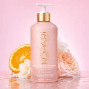 Kopari Brightening Silk Body Cream na tle z owocami i kwiatami, podkreślający efekt promiennej skóry.