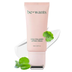 Różowa tubka liftingującego kremu do twarzy Bewants Cica Collagen z metalowym aplikatorem do masażu. W tle biała, kremowa konsystencja produktu. Obok tubki zielone listki wąkroty azjatyckiej, symbolizujące kluczowy składnik kremu. Produkt ma na celu ujędrnienie skóry, nawilżenie i redukcję zmarszczek.
