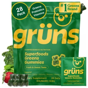 Zielone opakowanie Grüns Superfoods Greens Gummies 28 Pack z pojedynczą saszetką, zielonymi żelkami w kształcie misiów, jarmużem i truskawką na białym tle.