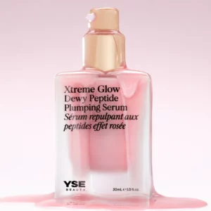 Packshot serum YSE Beauty Xtreme Glow – elegancka, matowa butelka w odcieniu różu ze złotą pompką, częściowo pokryta spływającym produktem, na jasnym tle podkreślającym jego lekką, płynną konsystencję.