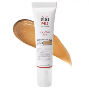 EltaMD UV AOX Eye SPF 30 – krem pod oczy z delikatnym kolorem i ochroną przeciwsłoneczną, trzymany w dłoni na beżowym tle z opisem działania rozświetlającego i zmniejszającego opuchnięcie.