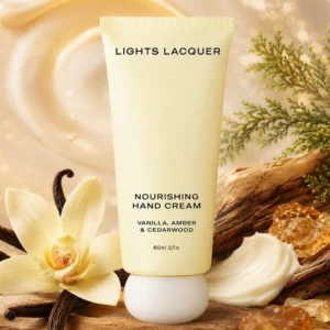 Krem do rąk Lights Lacquer Nourishing Hand Cream na tle wanilii, drewna cedrowego i bursztynowych dekoracji.