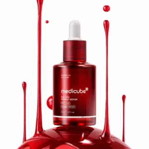 Szklana butelka Medicube EGF NAD Firming Serum w intensywnie czerwonym kolorze na jasnym tle. Serum otoczone dynamicznymi kroplami i płynną teksturą podkreślającą luksusowy, nowoczesny charakter pielęgnacji.