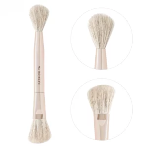 Packshot Patrick Ta Dual Ended Transition Blush Brush przedstawiający dwie końcówki pędzla: zaokrągloną do produktów płynnych oraz puszystą do pudrowych formuł.