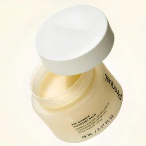 Prequel Pre-Gleanse Cleansing Balm - otwarte opakowanie balsamu oczyszczającego do demakijażu Prequel z uniesioną białą pokrywką, pokazane na jasnym minimalistycznym tle.