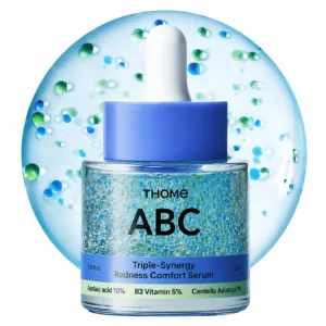 Serum Thome ABC Triple Synergy Redness Comfort Serum na jasnym tle z niebieskimi i zielonymi mikrokapsułkami. Lekka formuła z kwasem azelainowym, niacynamidem i centellą wspiera bardziej zrównoważony wygląd skóry.