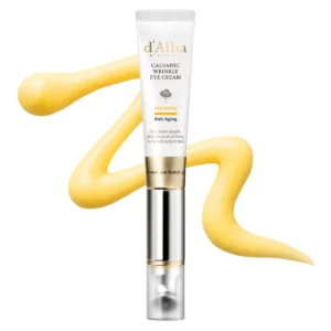 Minimalistyczne zdjęcie kremu pod oczy d’Alba Galvanic Wrinkle Eye Cream na jasnym tle. Produkt ustawiony pionowo na środku kadru, otoczony dekoracyjną smugą złocistego kremu podkreślającą rozświetlający charakter formuły.