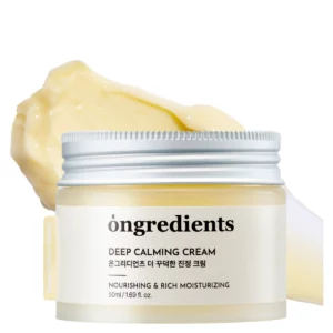 Packshot Ongredients Deep Calming Cream – kojący krem do twarzy w minimalistycznym słoiczku z metalową zakrętką. Obok produktu widoczna jest kremowa, bogata formuła o charakterystycznym delikatnie żółtym odcieniu.