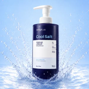 Dr.G Doopi Lab Cool Salt Scaling Shampoo w granatowej butelce z pompką, otoczonej rozbryzgami wody na niebieskim tle.