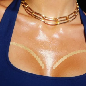 Na zdjęciu widoczny jest złoty kontur Fazit Cleavage Contour zaaplikowany na dekolt. Produkt subtelnie modeluje i rozświetla dekolt, tworząc efektowny makijaż ciała.