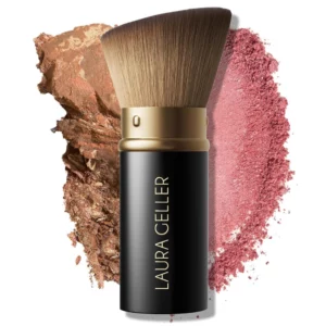 Laura Geller Angled Retractable Kabuki Brush na tle pudrowych tekstur w odcieniach różu i brązu, prezentujący zastosowanie do produktów sypkich i prasowanych.