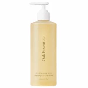 Butelka żelu do mycia ciała Oak Essentials Awaken Body Wash o pojemności 300 ml z białą pompką, przedstawiona na jasnym, neutralnym tle. Minimalistyczne opakowanie w kremowo-złotym odcieniu eksponuje elegancki design i luksusowy charakter produktu.