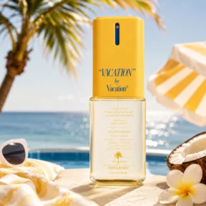 Vacation Body Mist w wakacyjnej scenerii przy basenie, z palmą, morzem, kokosem, kwiatem i żółtym ręcznikiem w tle.