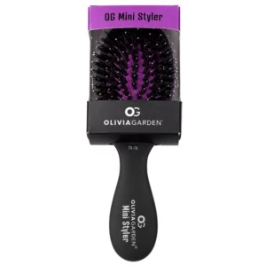 Szczotka Olivia Garden OG Mini Styler z rączką i czarnymi igłami, pokazana w oryginalnym opakowaniu na białym tle.