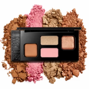 makeup 18 Na zdjęciu znajduje się otwarta paleta IL MAKIAGE High Point Face Shaping Palette z bronzerem, różowym różem i dwoma rozświetlaczami, ułożona na rozsypanych pigmentach w brązowych, różowych i złotych odcieniach na białym tle.