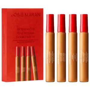 Josie Maran All Spritzed Up Mini Fragrance Discovery Set z czterema mini mgiełkami zapachowymi Topless Tangerine, Golden Hour, ...In Bed i Vanilla Vibezzz obok czerwonego opakowania.