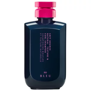 R+Co BLEU Soft Bounce Natural Texture & Curl Shampoo w granatowej butelce z intensywnie różową nakrętką na białym tle.