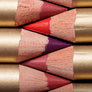 Start 107 Zbliżenie na kilka drewnianych konturówek do ust Aora Mexico Hablame Lip Liner Pencil w różnych odcieniach czerwieni, różu i śliwki, ułożonych warstwowo na czarnym tle.